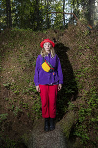 Woman wearing red bucket hat standing in forest