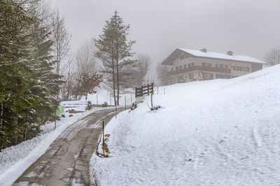 Snow covered road amidst buildings in city