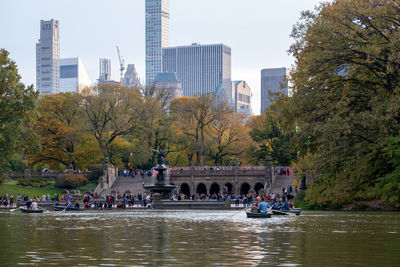 People by river against buildings in city