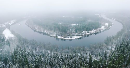 High angle view of river and forest in foggy weather during winter