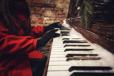 Midsection of woman playing abandoned piano during winter