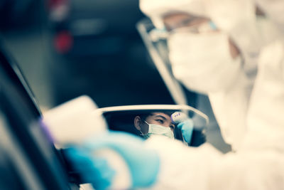 Asian woman drive thru covid-19 testing with ppe medical staff, covid testing temp while checking