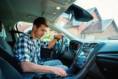 Young woman using mobile phone while sitting in car