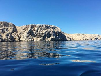 Surface level of calm lake against clear blue sky