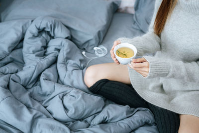 Midsection of woman sleeping on bed at home