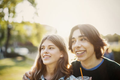 Happy teenagers looking away at park