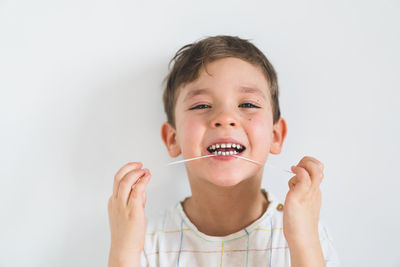 Cute boy pulling loose tooth using a dental floss. process of removing a baby tooth.