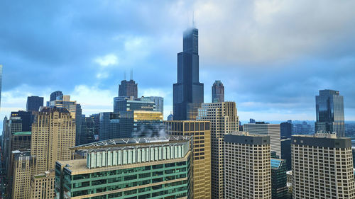 Modern buildings in city against cloudy sky