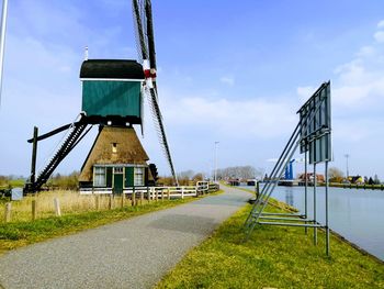 Windmill by river against sky