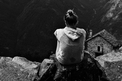 Rear view of woman sitting on rock