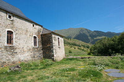 Building by mountains against clear blue sky