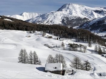 Snow covered landscape against snowcapped mountains