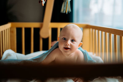 Baby boy toddler crawling in crib at kids nursery room at home. looking and smiling at the camera