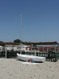 Sailboats moored on beach against clear blue sky