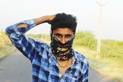 Portrait of young man wearing balaclava while standing on land against sky