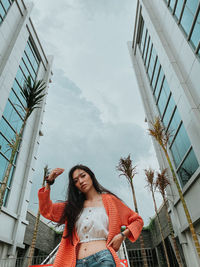 Low angle view of woman standing against building in city