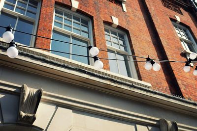 Low angle view of light bulbs hanging against residential building