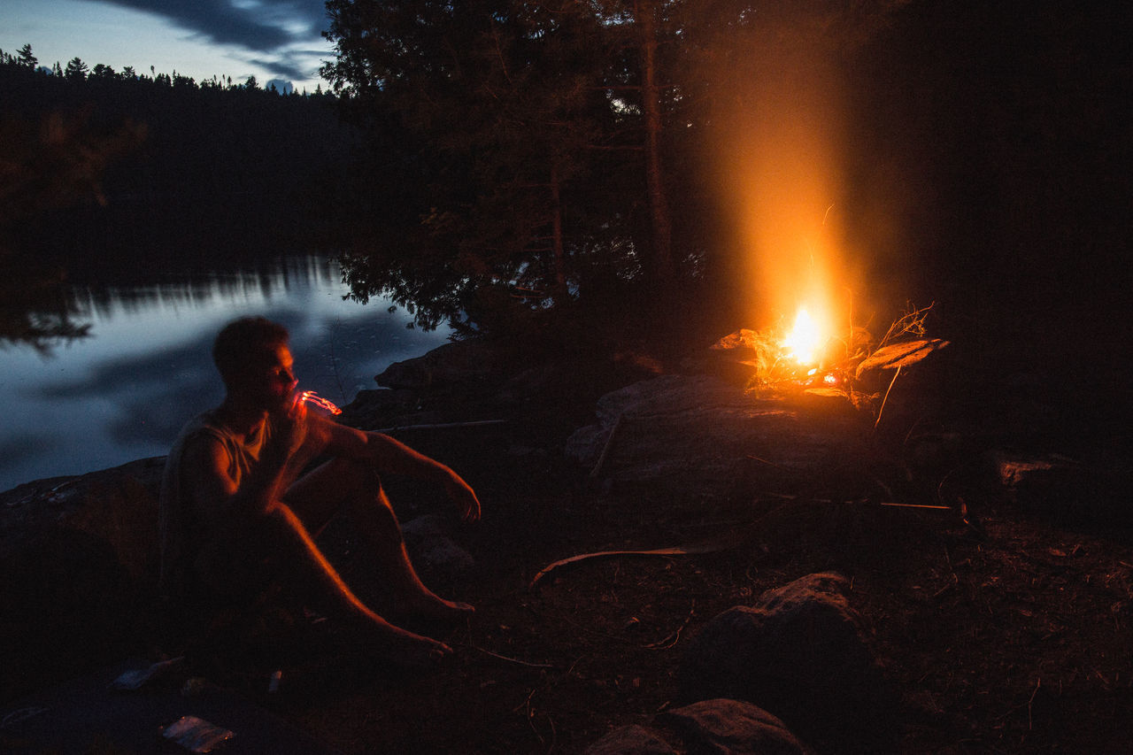 REFLECTION OF MAN SITTING ON FIRE IN BONFIRE