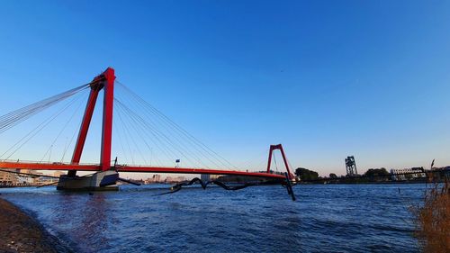 Suspension bridge over river against clear blue sky