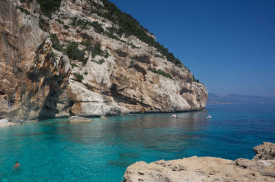 Scenic view of sea and mountains against clear blue sky