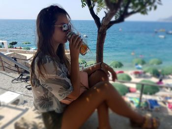 Young woman drinking water from beach