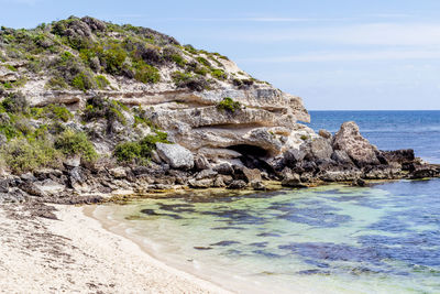 Rock formation on beach against sky