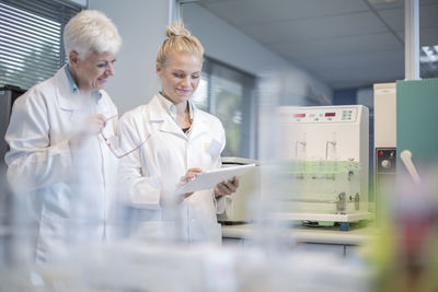 Two smiling women in lab looking at tablet together