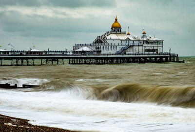 Built structure in sea against cloudy sky