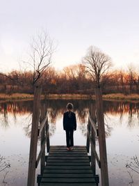 Rear view of girl standing on pier over lake