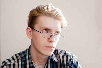 Portrait of teenage boy wearing eyeglasses against white background
