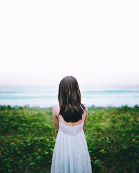 Rear view of woman looking at sea against clear sky