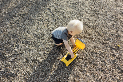 High angle view of boy playing with toy earthmover on ground