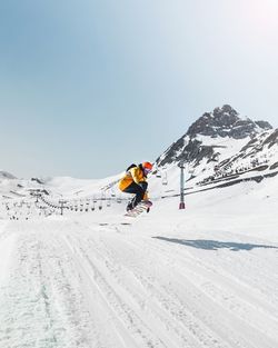 Man snowboarding against snowcapped mountains during winter