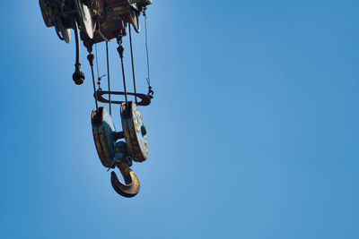Low angle view of chain hanging against clear blue sky