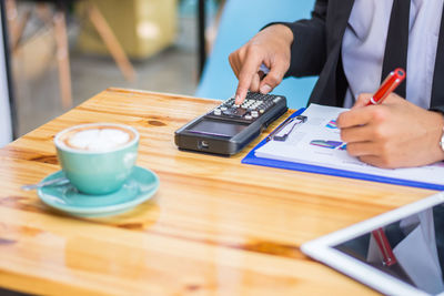 Midsection of man holding camera on table