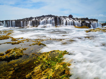 Scenic view of waterfall against sky