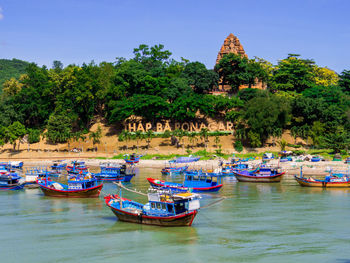 Boats moored in river against clear blue sky