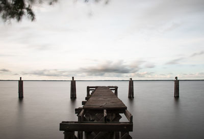 Wooden pier over sea against sky