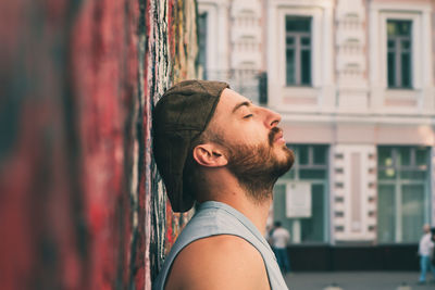 Portrait of young man looking away against wall