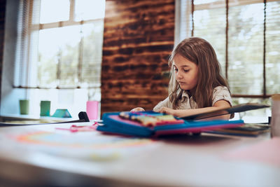 Girl doing homework, learning, drawing pictures, doing puzzles in school library. primary school