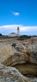 Lighthouse on rock formation against sky