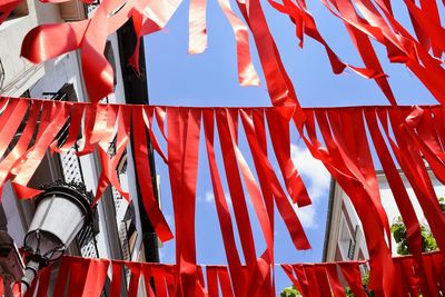 Low angle view of red paper strips hanging against the sky