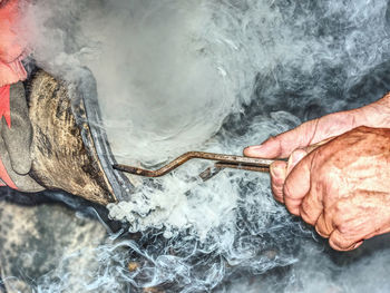 Blacksmiths pliers hold horseshoe on hoof for shape comparison and accurate horseshoe fit.