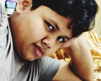 Close-up portrait of smiling boy on bed