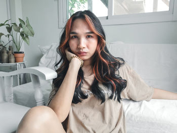 Portrait of young woman sitting on bed at home