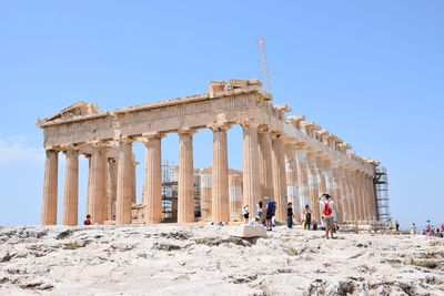 Tourists at historical building against clear sky