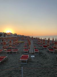 Chairs on beach against clear sky during sunset