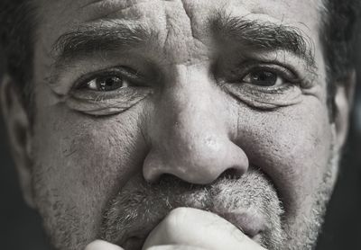 Close-up portrait of mature man against black background