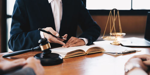 Midsection of lawyer with client in courtroom