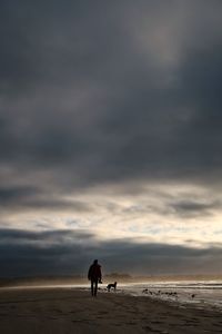 Men on beach against sky during sunset